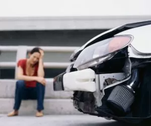 woman stressed sitting on curb after car accident