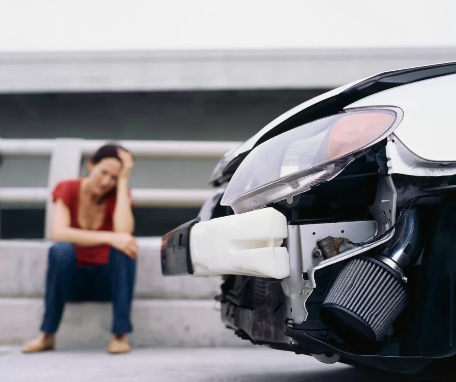 woman stressed sitting on curb after car accident